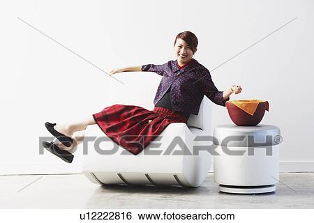 Portrait of a young woman sitting on a couch smiling View Large Photo Image Stock Photograph - Portrait of a young woman sitting on a couch smiling. Fotosearch