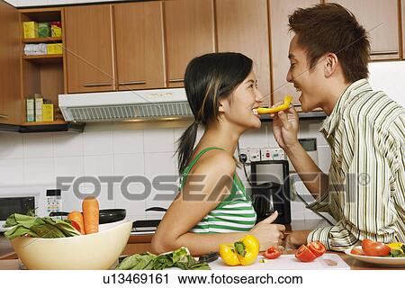 Side profile of a young man feeding a slice of yellow bell pepper to a young woman at a kitchen counter View Large Photo Image Stock Image - Side profile of a young man feeding a slice of yellow bell pepper to a young woman at a kitchen counter. Fotosearch