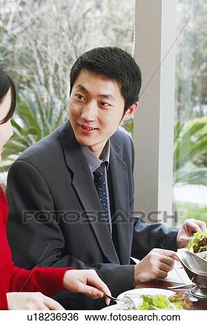 Stock Photograph - Young man and a young woman seated at the table in a restaurant. Fotosearch