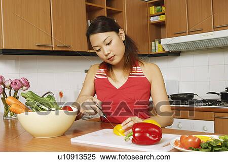 Young woman cutting vegetables at a kitchen counter View Large Photo Image Stock Photography - Young woman cutting vegetables at a kitchen counter. Fotosearch