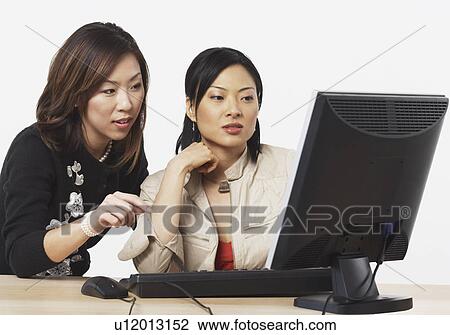 Close-up of two businesswomen looking at a computer View Large Photo Image Stock Image - Close-up of two businesswomen looking at a computer. Fotosearch