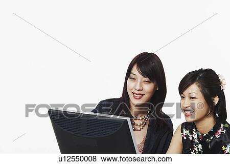 Stock Photo - Close-up of two businesswomen using a computer. Fotosearch
