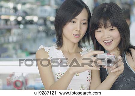 Stock Image - Close-up of two young women holding a camera. Fotosearch