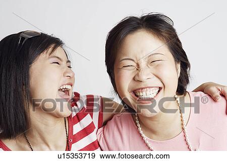Stock Photo - Close-up of two young women looking cheerful. Fotosearch