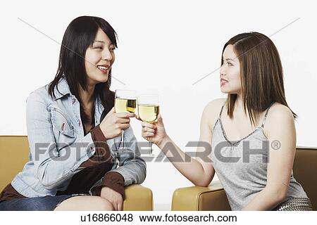 Stock Photo - Close-up of two young women toasting with wineglasses. Fotosearch