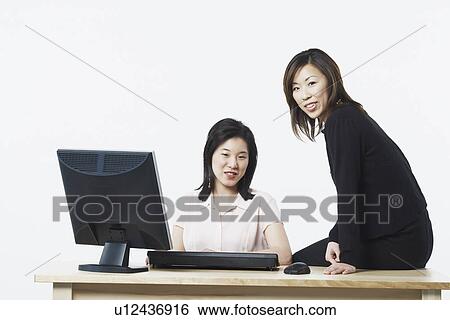 Portrait of two businesswomen smiling in front of a computer View Large Photo Image Stock Photograph - Portrait of two businesswomen smiling in front of a computer. Fotosearch