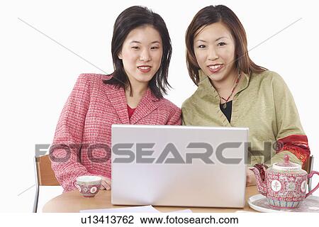 Stock Image - Portrait of two businesswomen using a laptop. Fotosearch