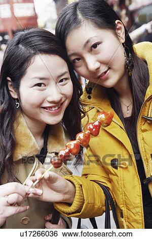 Portrait of two young women holding strawberries on a stick View Large Photo Image Stock Photograph - Portrait of two young women holding strawberries on a stick. Fotosearch