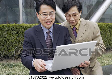 Two businessmen using a laptop View Large Photo Image Stock Image - Two businessmen using a laptop. Fotosearch