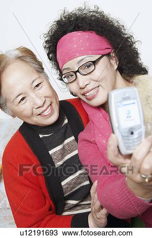 Stock Image - Two mature women taking a photograph. Fotosearch