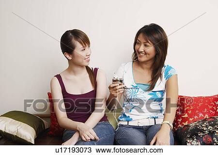 Two young women listening to an MP3 player View Large Photo Image Stock Image - Two young women listening to an MP3 player. Fotosearch