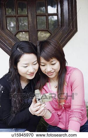 Two young women looking at a digital camera smiling View Large Photo Image Stock Image - Two young women looking at a digital camera smiling. Fotosearch