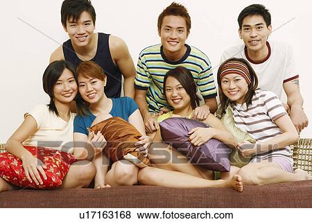 Close-up of four women sitting on a couch with three young men standing behind them View Large Photo Image Stock Photo - Close-up of four women sitting on a couch with three young men standing behind them. Fotosearch