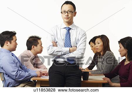 Portrait of a businessman in a meeting with business executives behind him View Large Photo Image Stock Photo - Portrait of a businessman in a meeting with business executives behind him. Fotosearch