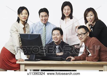 Picture - Portrait of a group of business executives smiling in front of a computer. Fotosearch