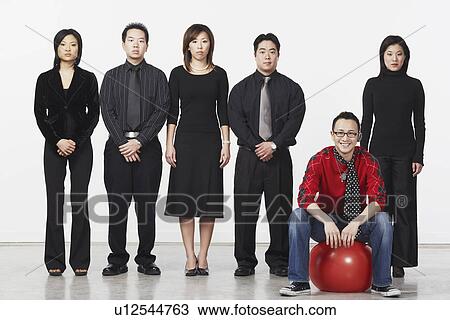 Portrait of a young man sitting on a ball with a group of business executives standing beside him View Large Photo Image Stock Image - Portrait of a young man sitting on a ball with a group of business executives standing beside him. Fotosearch