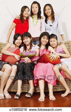 Portrait of three young women standing behind their friends sitting on a couch View Large Photo Image Stock Photograph - Portrait of three young women standing behind their friends sitting on a couch. Fotosearch