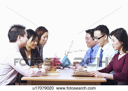 Stock Image - Three businessmen and three businesswomen sitting on chairs in a meeting. Fotosearch