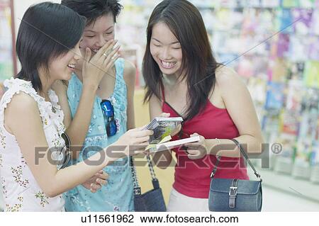 Stock Image - Three young women standing in a record store. Fotosearch