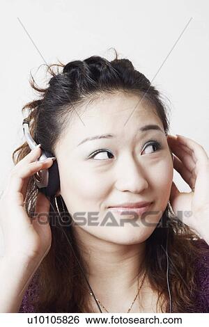 Stock Photograph - Close-up of a young woman listening to music. Fotosearch