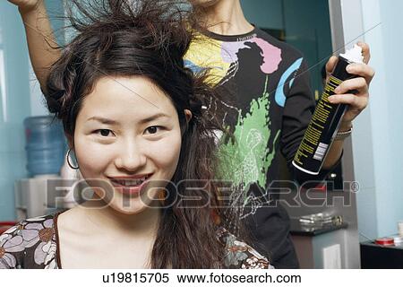 Stock Photography - Male hairdresser styling a young woman's hair. Fotosearch