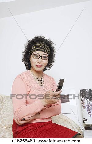 Stock Image - Portrait of a mature woman using a mobile phone. Fotosearch