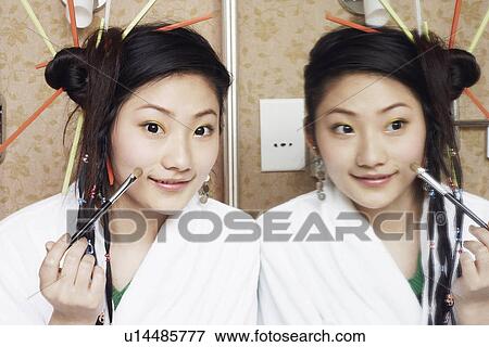 Portrait of a teenage girl applying make-up on her face View Large Photo Image Stock Photo - Portrait of a teenage girl applying make-up on her face. Fotosearch