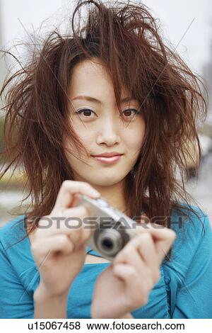 Portrait of a young woman holding a digital camera View Large Photo Image Stock Photo - Portrait of a young woman holding a digital camera. Fotosearch