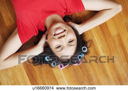 Picture - Portrait of a young woman lying on a hardwood floor and smiling. Fotosearch