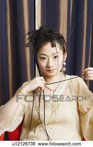 Portrait of a young woman sitting on a chair View Large Photo Image Stock Photo - Portrait of a young woman sitting on a chair. Fotosearch