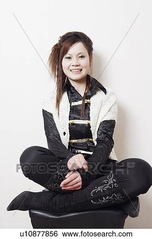 Stock Photograph - Portrait of a young woman sitting cross-legged. Fotosearch