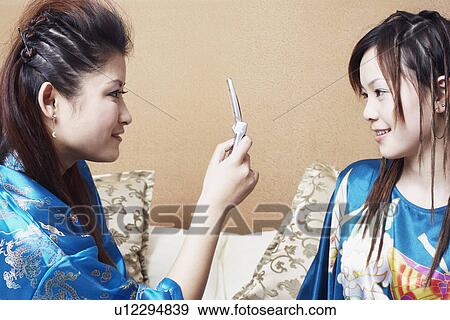 Side profile of a teenage girl taking a photograph of a young woman View Large Photo Image Stock Photo - Side profile of a teenage girl taking a photograph of a young woman. Fotosearch
