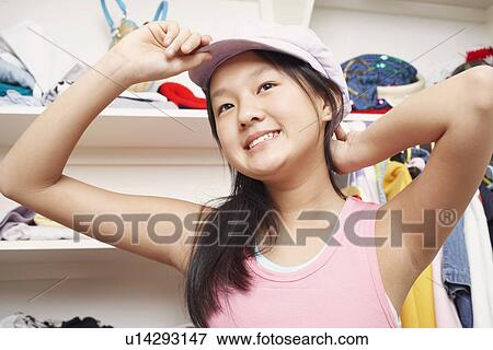 Stock Photo - Low angle view of a girl holding a cap smiling. Fotosearch