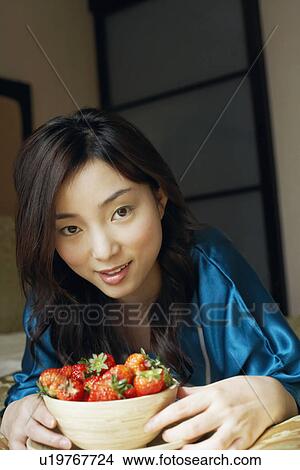 Portrait of a young woman holding a bowl full of strawberries smiling View Large Photo Image Picture - Portrait of a young woman holding a bowl full of strawberries smiling. Fotosearch