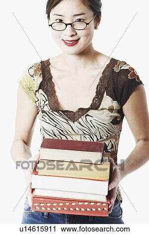Stock Image - Portrait of a young woman holding books and smiling. Fotosearch