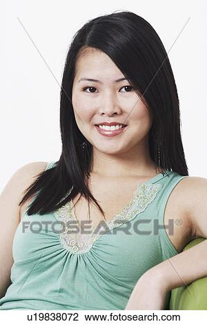 Portrait of a young woman sitting on a couch smiling View Large Photo Image Stock Image - Portrait of a young woman sitting on a couch smiling. Fotosearch