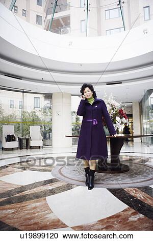 Stock Image - Businesswoman standing and talking on a mobile phone. Fotosearch