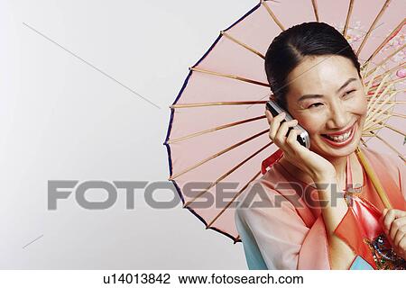Stock Image - Close-up of a mid adult woman talking on a mobile phone and smiling. Fotosearch