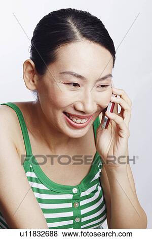 Stock Photo - Close-up of a mid adult woman talking on a mobile phone and smiling. Fotosearch