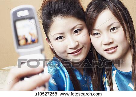 Stock Photo - Close-up of a teenage girl and a young woman taking a photograph of themselves. Fotosearch
