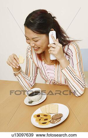 Close-up of a young woman holding a cookie and talking on a mobile phone View Large Photo Image Stock Photo - Close-up of a young woman holding a cookie and talking on a mobile phone. Fotosearch