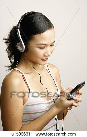 Stock Image - Close-up of a young woman listening to music and operating a mobile phone. Fotosearch
