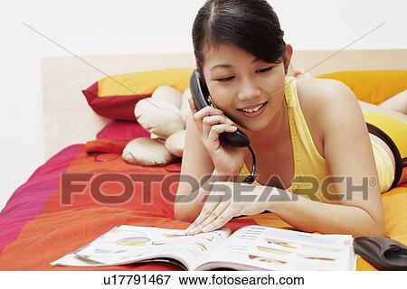 Close-up of a young woman talking on the telephone and reading a magazine View Large Photo Image Stock Photo - Close-up of a young woman talking on the telephone and reading a magazine. Fotosearch