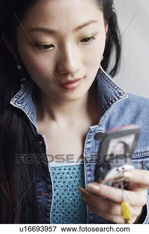 Stock Photo - Close-up of a young woman using a mobile phone. Fotosearch