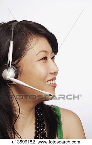 Stock Image - Close-up of a young woman wearing a headset and smiling. Fotosearch