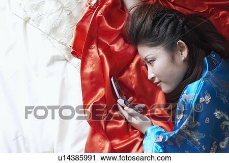 High angle view of a young woman holding a mobile phone View Large Photo Image Stock Image - High angle view of a young woman holding a mobile phone. Fotosearch