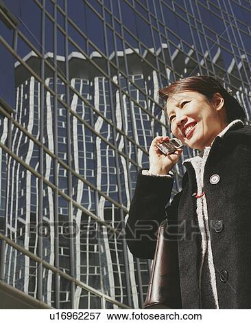 Stock Photo - Low angle view of a young woman talking on a mobile phone. Fotosearch