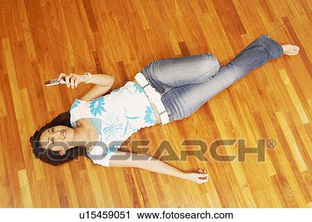 Portrait of a young woman lying on a hardwood floor and holding a mobile phone View Large Photo Image Stock Image - Portrait of a young woman lying on a hardwood floor and holding a mobile phone. Fotosearch