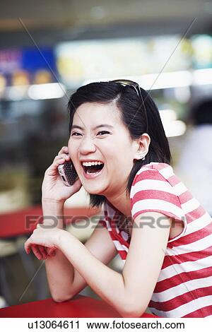 Portrait of a young woman talking on a mobile phone and laughing View Large Photo Image Stock Image - Portrait of a young woman talking on a mobile phone and laughing. Fotosearch