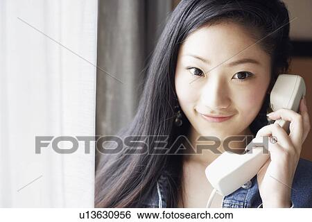 Stock Photograph - Portrait of a young woman talking on the telephone. Fotosearch
